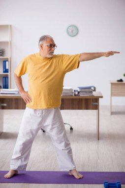 Ofiste spor egzersizleri yapan eski bir işadamı.