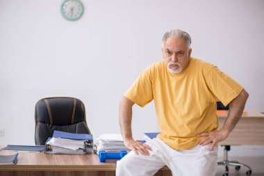 Ofiste spor egzersizleri yapan eski bir işadamı.