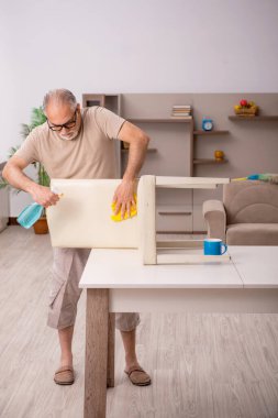 Yaşlı adam evde ev işi yapıyor.