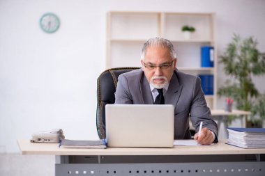 Ofiste çalışan yaşlı bir erkek.