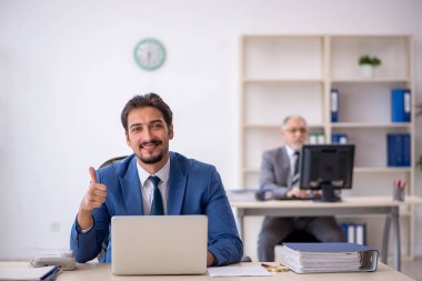 Yaşlı erkek patron ve ofiste çalışan genç erkek çalışan.