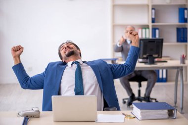 Yaşlı erkek patron ve ofiste çalışan genç erkek çalışan.