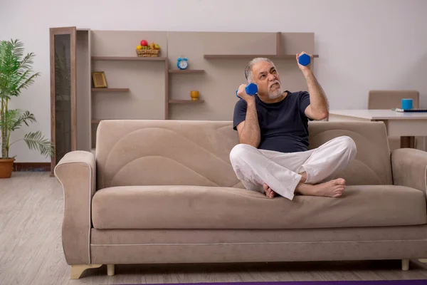 Old man doing sport exercises at home — Stock Photo, Image