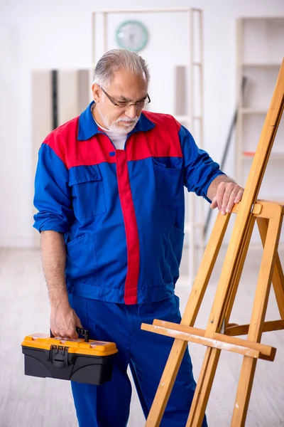 Старий чоловік столяр ремонтує креслення мольберта — стокове фото