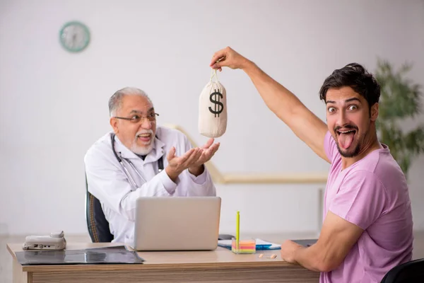 Jovem do sexo masculino visita velho do sexo masculino médico em remuneração conc — Fotografia de Stock