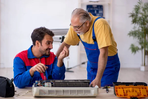 Twee mannelijke reparateurs repareren airconditioner — Stockfoto