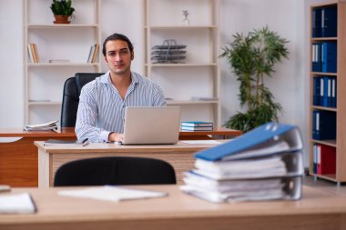 Genç erkek çalışan ofiste oturuyor.