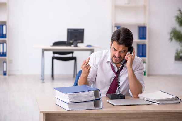 Joven empleado masculino descontento con el trabajo excesivo en la oficina —  Fotos de Stock