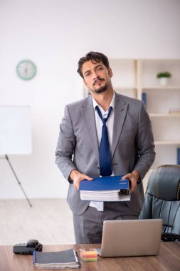 Genç erkek çalışan ofiste oturuyor.