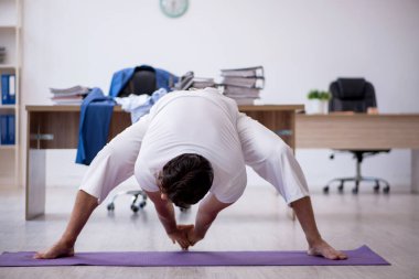 Genç erkek çalışan ofiste spor egzersizleri yapıyor.
