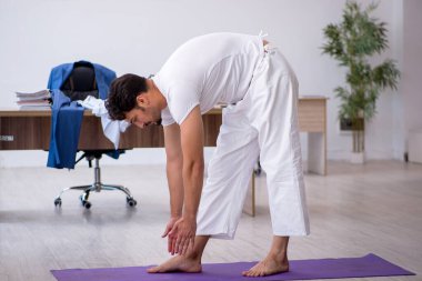 Genç erkek çalışan ofiste spor egzersizleri yapıyor.