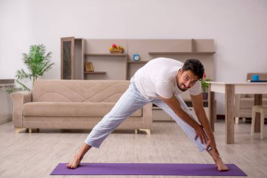 Genç adam evde spor yapıyor.