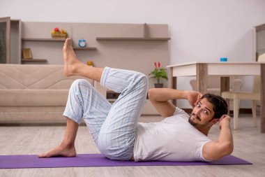 Genç adam evde spor yapıyor.