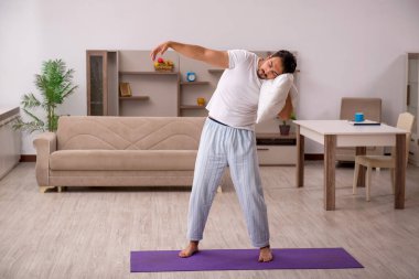 Genç adam evde spor yapıyor.