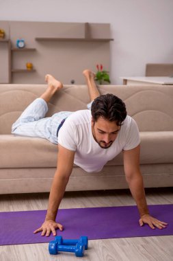 Genç adam evde spor yapıyor.