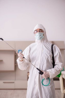 Genç erkek müteahhit evde haşere kontrolü yapıyor.