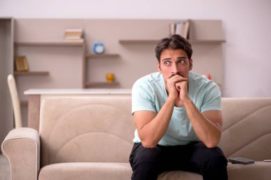 Genç adam kanepede oturuyor.