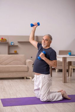 Yaşlı adam evde spor yapıyor.