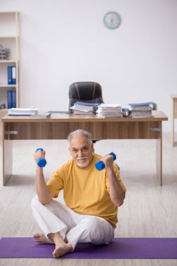 Ofiste spor egzersizleri yapan eski bir işadamı.