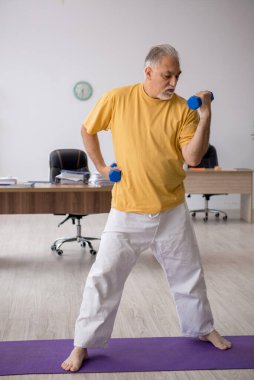 Ofiste spor egzersizleri yapan eski bir işadamı.