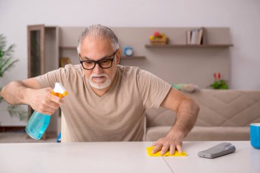 Yaşlı adam evde ev işi yapıyor.