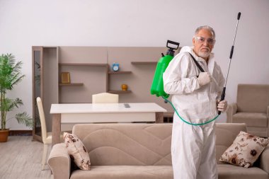 Yaşlı erkek müteahhit evde haşere kontrolü yapıyor.