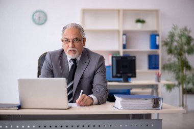Ofiste çalışan yaşlı bir erkek.