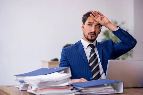 Joven empleado masculino y demasiado trabajo en la oficina — Foto de Stock