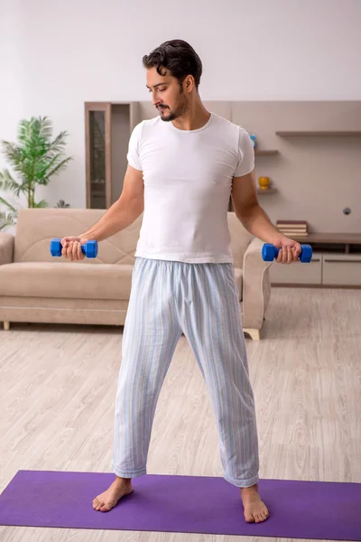 Jovem fazendo exercícios esportivos em casa — Fotografia de Stock