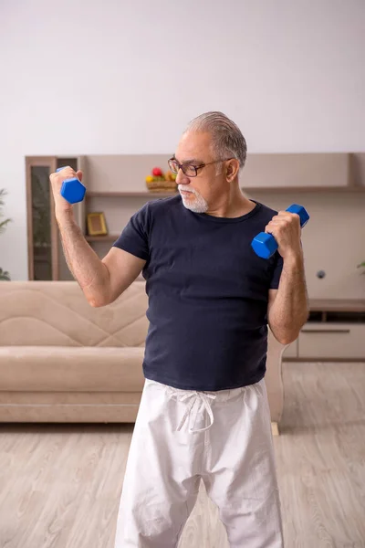 Starý muž dělá sportovní cvičení doma — Stock fotografie