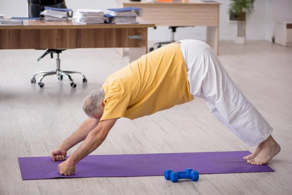 Ein alter Geschäftsmann macht Sport im Büro — Stockfoto