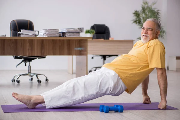 Velho empresário empregado fazendo exercícios esportivos no escritório — Fotografia de Stock