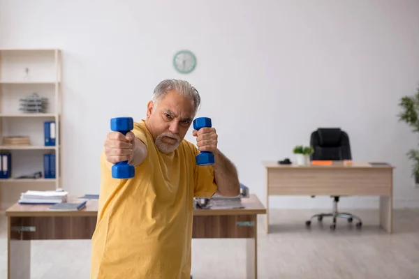 Ein alter Geschäftsmann macht Sport im Büro — Stockfoto