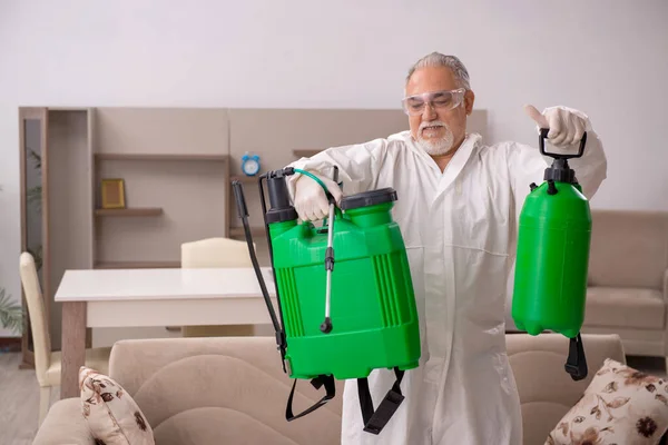 Old male contractor doing pest control at home — Stock Photo, Image