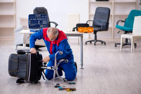 Homem velho reparador reparando cadeira de escritório — Fotografia de Stock