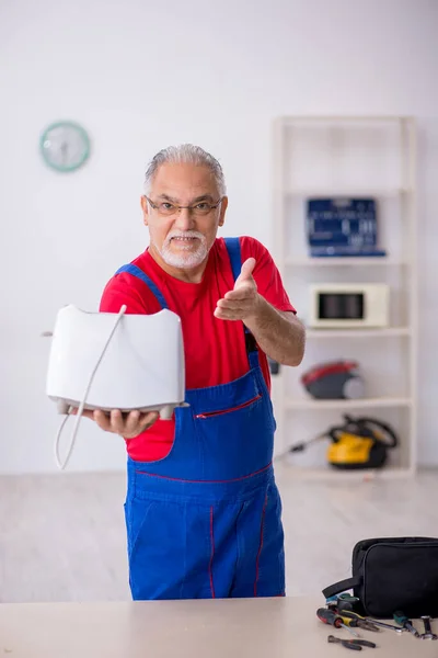Vecchio riparatore che ripara tostapane in officina — Foto Stock