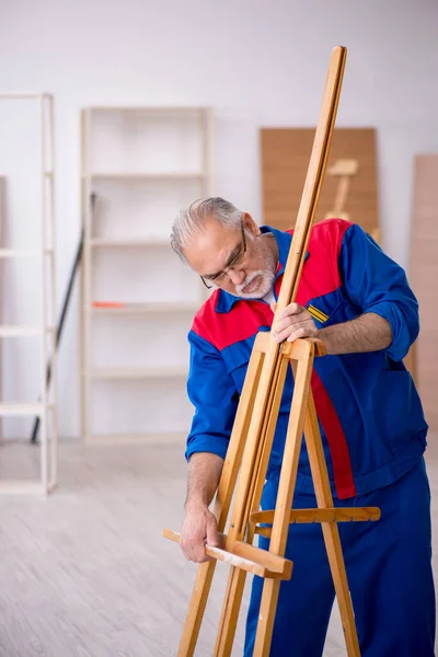 Old male carpenter repairing drawing easel — Stock Photo, Image