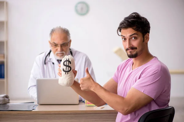 Fiatal férfi beteg látogató idős férfi orvos javadalmazás conc — Stock Fotó