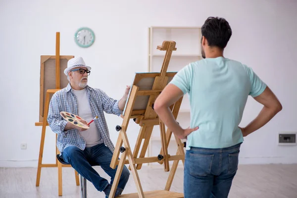 Viejo pintor y joven modelo masculino en el estudio — Foto de Stock