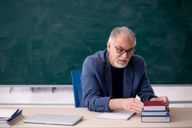 Sınıftaki yaşlı erkek öğretmen.