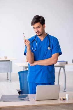 Klinikte çalışan genç erkek doktor.