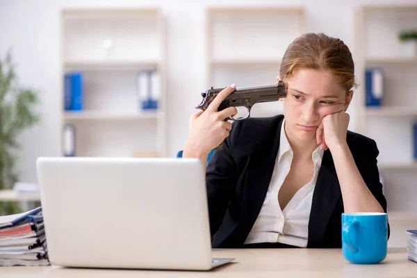 Joven empleada sosteniendo arma en la oficina — Foto de Stock