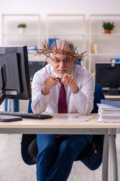 Old male employee wearing prickly wreath on head — Stock Photo, Image