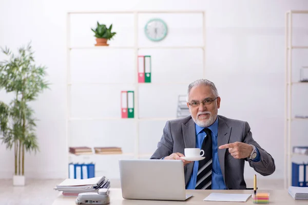 Gammal manlig anställd dricker kaffe under rasten — Stockfoto