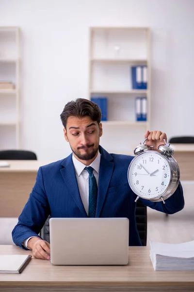 Joven empleado masculino en concepto de gestión del tiempo —  Fotos de Stock