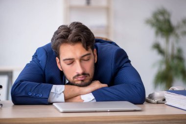 Genç erkek çalışan ofiste çok yorgun.