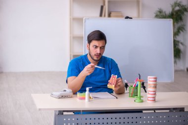Genç dişçi hocası beyaz tahtanın önünde.