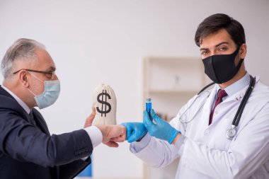 Yaşlı işadamı aşı danışmanıyla genç erkek doktoru ziyaret ediyor.