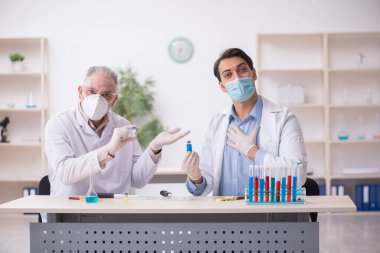 Salgın sırasında laboratuvarda çalışan iki erkek kimyager.