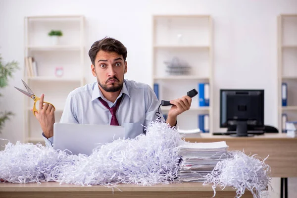 Młody pracownik płci męskiej i dużo papierów ciętych w biurze — Zdjęcie stockowe